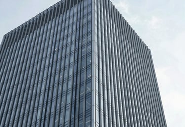 A minimalist photograph of an architectural detail of a modern skyscraper, showing clear glass and steel lines against a bright sky. The focus is on the upward trajectory and precision of the design.