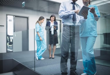 Equipo médico profesional es asesorado por ejecutivos de negocios revisando datos en una tableta