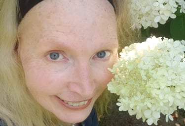 Acupuncturist and author Jean Brannon smiles among hydrangea blossoms.