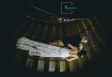 Mariés descendant un escalier en colimaçon vue d’en haut, robe dentelle et costume noir.