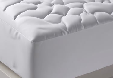 A neatly made bed featuring a crisp white mattress protector.
