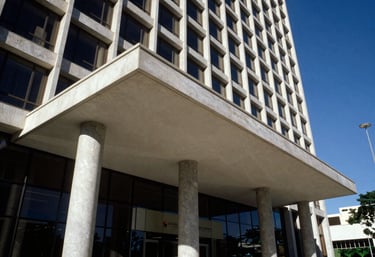 An architectural detail of a modern corporate building entrance in Brazil, focusing on structural strength and professional design, with a deep blue sky backdrop.