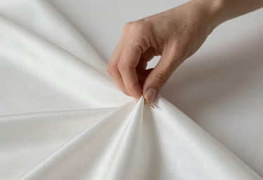 Close-up of hands sewing fine lingerie fabric with precision and care.