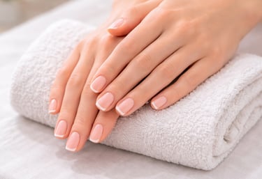Elegant French manicure on manicured hands resting on a clean white spa towel.