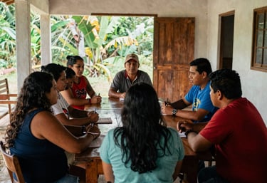 A crisp South American / Brazilian Amazonian documentary photograph of a cultural management workshop. Art leaders gather around a table in an airy community center in Santa Bárbara do Pará, high contrast lighting.