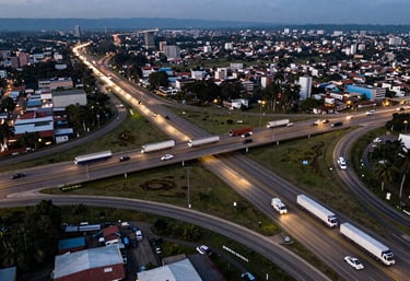 A wide aerial photography shot of a large, busy highway interchange in South America at dusk, with trails of lights from trucks and vehicles, symbolizing a dynamic and moving economy.