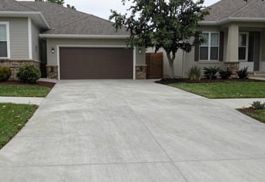 A freshly poured concrete driveway with clean lines and a smooth finish under a bright sky.
