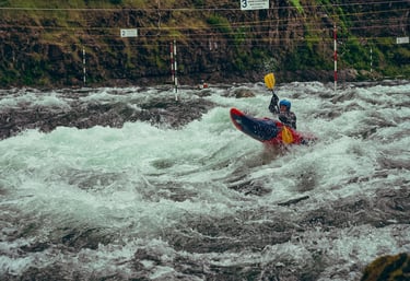 Woman kayaking down a rapid in a river through slalom gates during a race.
