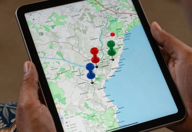 A close-up of a hand holding a modern tablet showing a map of Pakistan with pins on major cities, South Asian Pakistani attire visible on the sleeve.