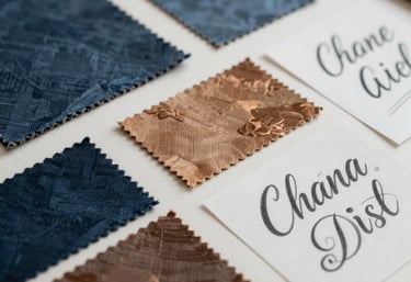 Detailed view of a moodboard with fabric samples, color swatches in blue and bronze, and typographic sketches. Latin American / Hispanic creative studio, soft daylight.