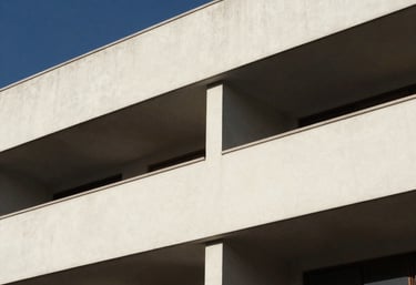 Clean, artistic shot of architectural elements in a modern Latin American building. Strong shadows, off-white and deep blue tones, minimalist professional feel.