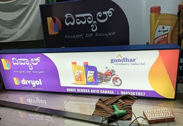 Illuminated shop signboard for Divyol lubricants and Gandhar oil at Shree Renuka Auto Garage.