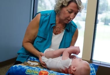 Dr. Naas performing a gentle chiropractic exam on an infant while supporting the baby’s comfort and alignment.