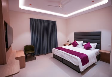 Modern hotel bedroom featuring a king bed with purple accents and ambient cove lighting.
