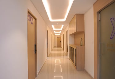 Modern hotel corridor with sleek wooden doors, recessed ceiling lighting, and polished tile floors.
