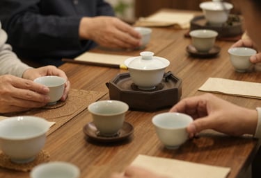 Close-up of a steaming cup of green tea beside loose tea leaves on a dark wooden table.