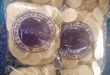 Stacks of white communion wafers altar bread in bags from Holy Family Sisters.