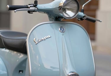 Close-up of a sleek electric Vespa's handlebar and vintage design details under natural light.