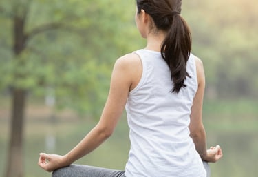 A serene woman practicing breathing exercises in a softly lit room with green and terracotta accents.