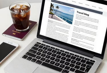 A cozy workspace with a laptop open to a travel blog page, surrounded by travel guides and a cup of coffee.