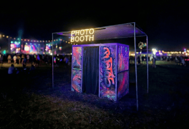 a enclosed photobooth with cool uv reactive art at a music festival at night