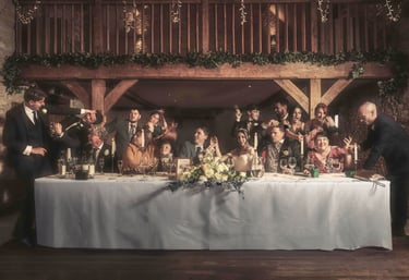 Wedding party celebrating at a long head table in a rustic barn venue with floral decor.