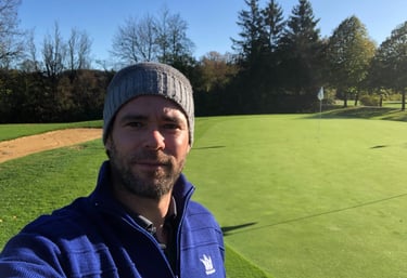 a man in a blue jacket and a hat on a golf course
