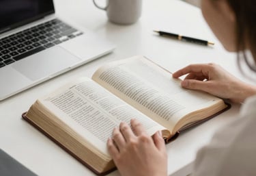 A warm, inviting workspace with a laptop, a cup of coffee, and an open prayer journal bathed in soft natural light.