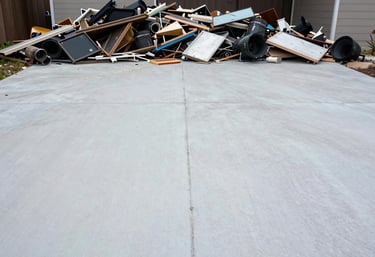 A clean, empty driveway where a junk pile used to be, now showing only the clean Pale Mist pavement, conveying a sense of professional completion.