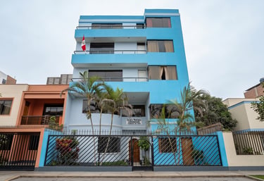 Exterior view of the blue Escuela Misiologica Latinoamericana building in Peru with palm trees and a gate.