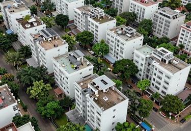 Aerial view of a clean, well-planned South Asian urban residential neighborhood with lush greenery and white buildings.