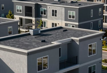 A modern multi-level residential building with flat rubber roofs, featuring clean architecture and gray-toned materials, North American suburban environment.