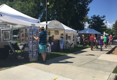 Art booths at Art in the Park with people walking around shopping for art