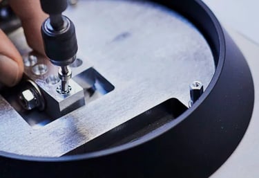 A technician using a precision tool to tighten a screw on an aluminum mechanical assembly.