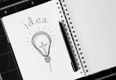 Hand-drawn light bulb sketch with the word idea in a spiral notebook, symbolizing creative brainstorming.