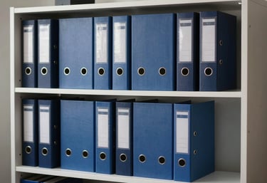 A minimalist, organized office bookshelf featuring professional binders in soft steel blue and dark navy tones.