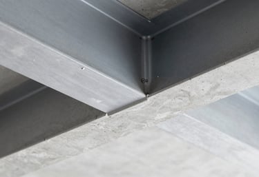 Detailed close-up of high-quality concrete finishing meeting a steel beam. The image emphasizes the clean lines and material quality inherent in professional construction, featuring a palette of #A0AEC0 and #4A5568.