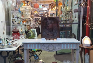 Vitrine de la brocante de l'Ardèche avec des petits meubles et nombreux bibelots.