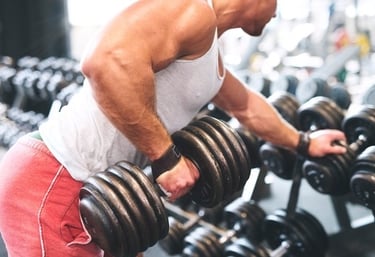 A muscular man performing a single-arm dumbbell row for back strength training in a gym setting.
