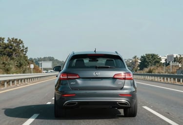 A flatbed truck carefully carrying a car on a sunny day.