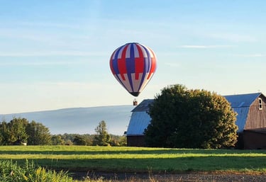 a hot air balloon in the sky over a barn