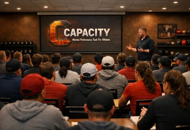 A speaker presenting Capacity mental performance tools for athletes to a large seated audience.