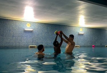 a Boy reaching for toys in the pool with 2 instructors