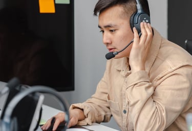a man in a tan jacket and headphones on a laptop