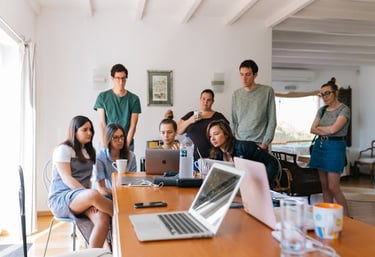 A team gathered around a laptop on a table, attending a virtual meeting.