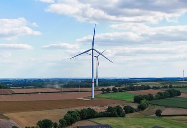 Landschap met een windturbine in Zichem, omgeven door landbouwvelden en bomen onder een deels bewolkte heme