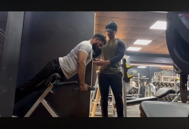 A focused coach teaching his client how to perform hyperextension exercise