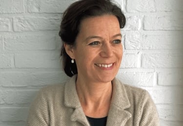 a woman in a beige jacket and earrings