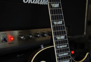A Les Paul guitar leaning against a Marshall amplifier.
