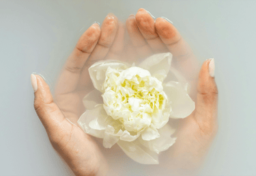 a person holding a flower in their hands with manicure